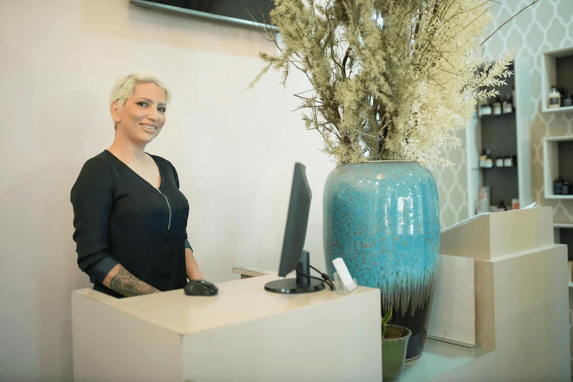 Salon receptionist managing appointment bookings on a desktop computer at a modern front desk